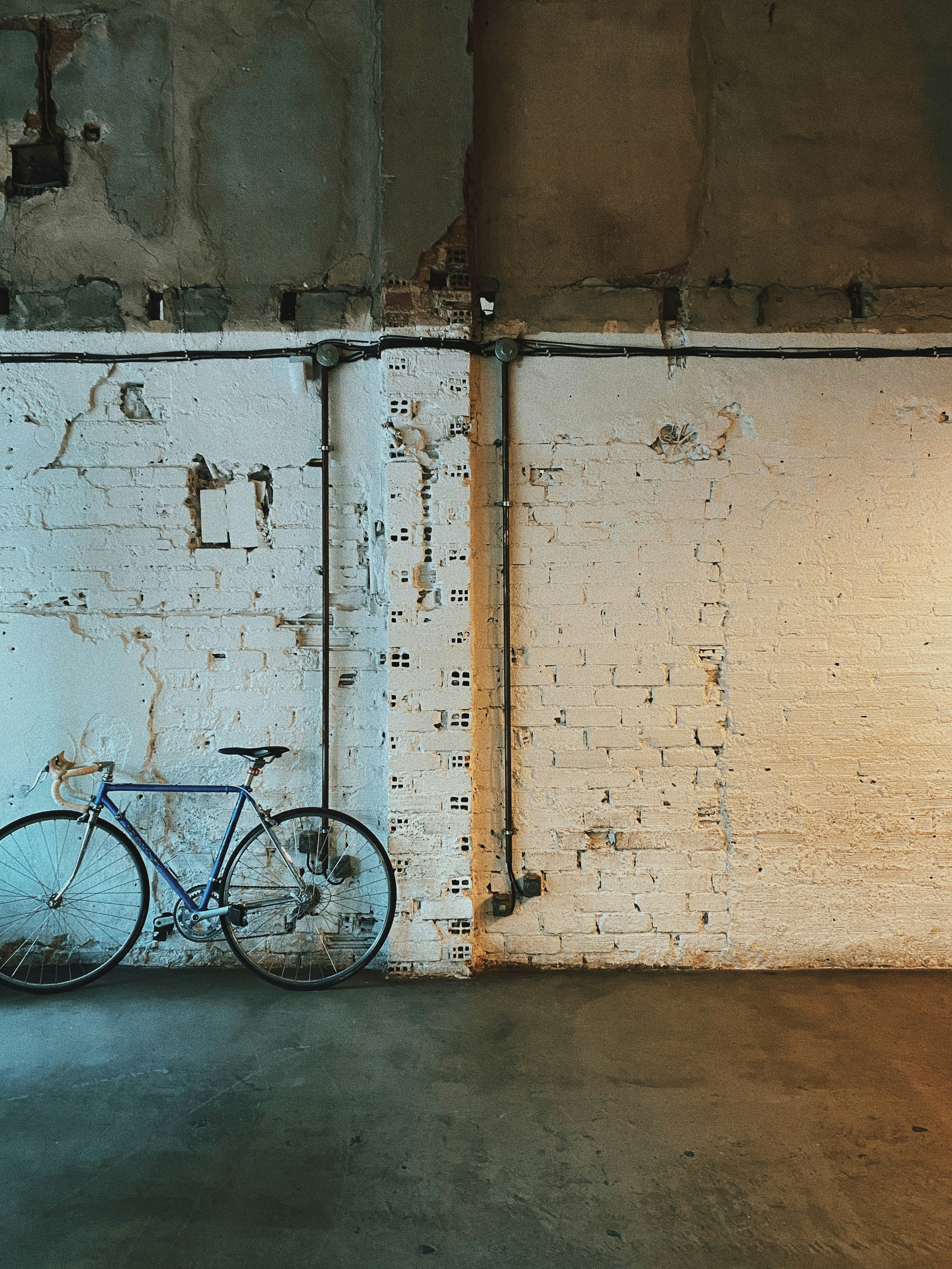 blue city bike leaning on white wall